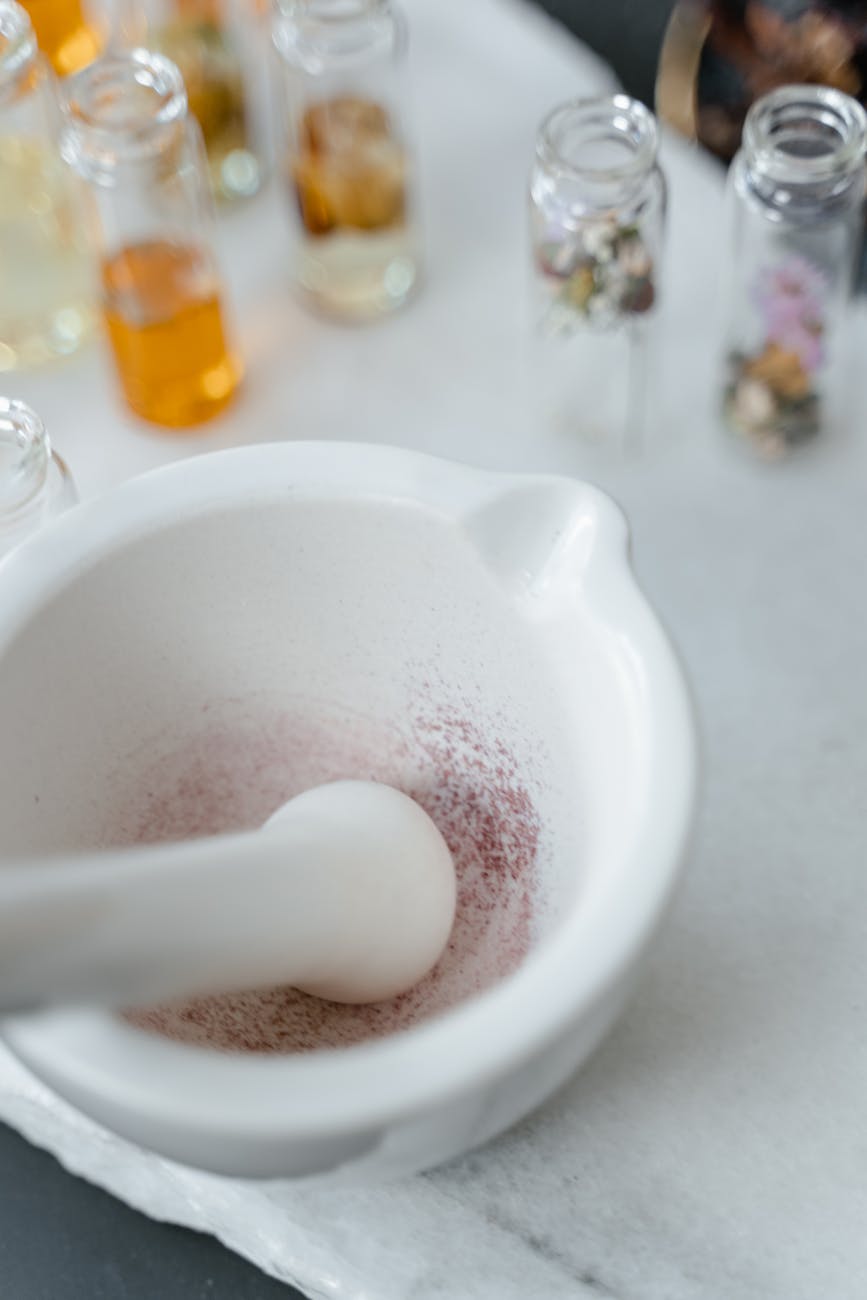 white marble mortar and pestle beside glass bottles