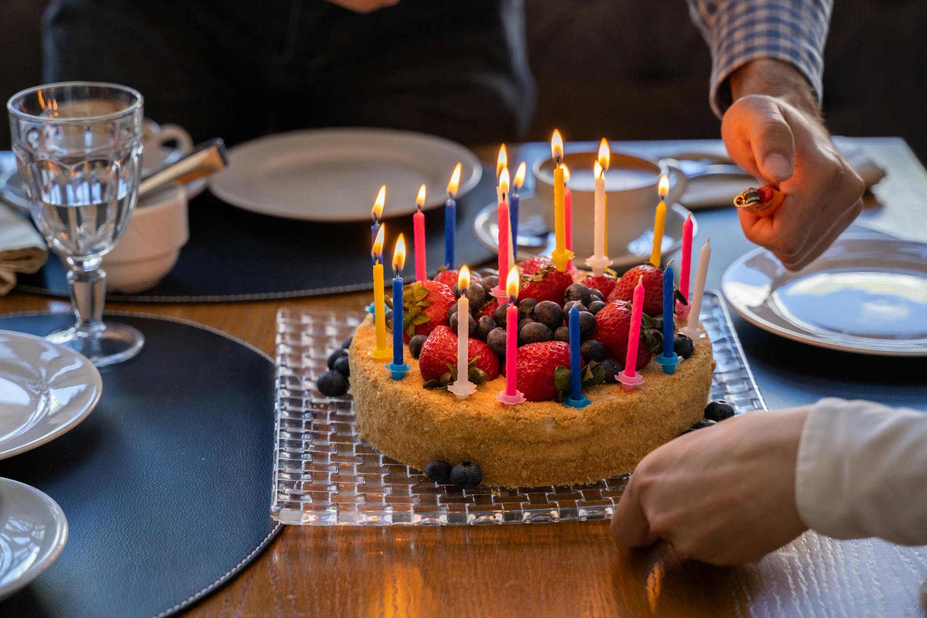 person lighting candles on a cake